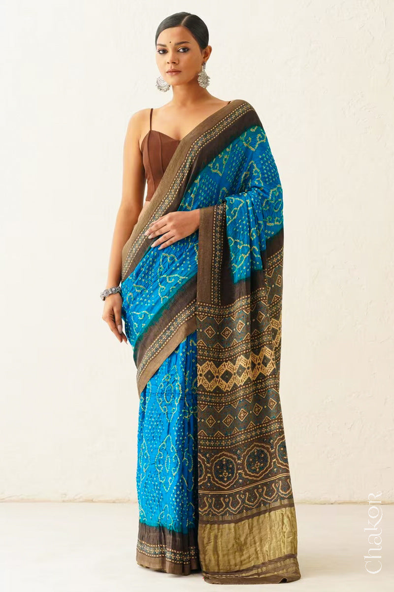 Woman wearing Peacock Blue Bandhani Saree with Brown Ajrakh printed border and pallu in pure gaji silk with traditional bandhej tie-dye, handcrafted in Kutch. 