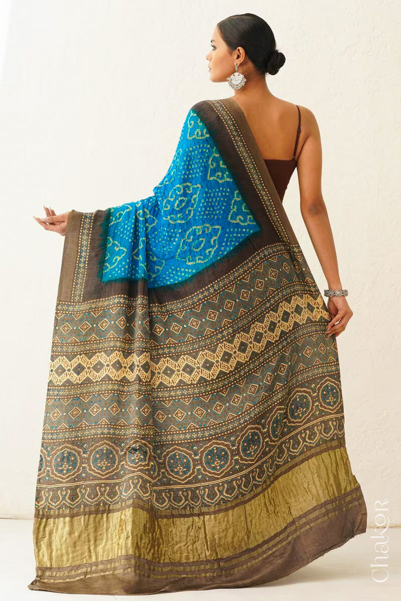 Woman wearing Peacock Blue Bandhani Saree with Brown Ajrakh printed border and pallu in pure gaji silk with traditional bandhej tie-dye, handcrafted in Kutch. 