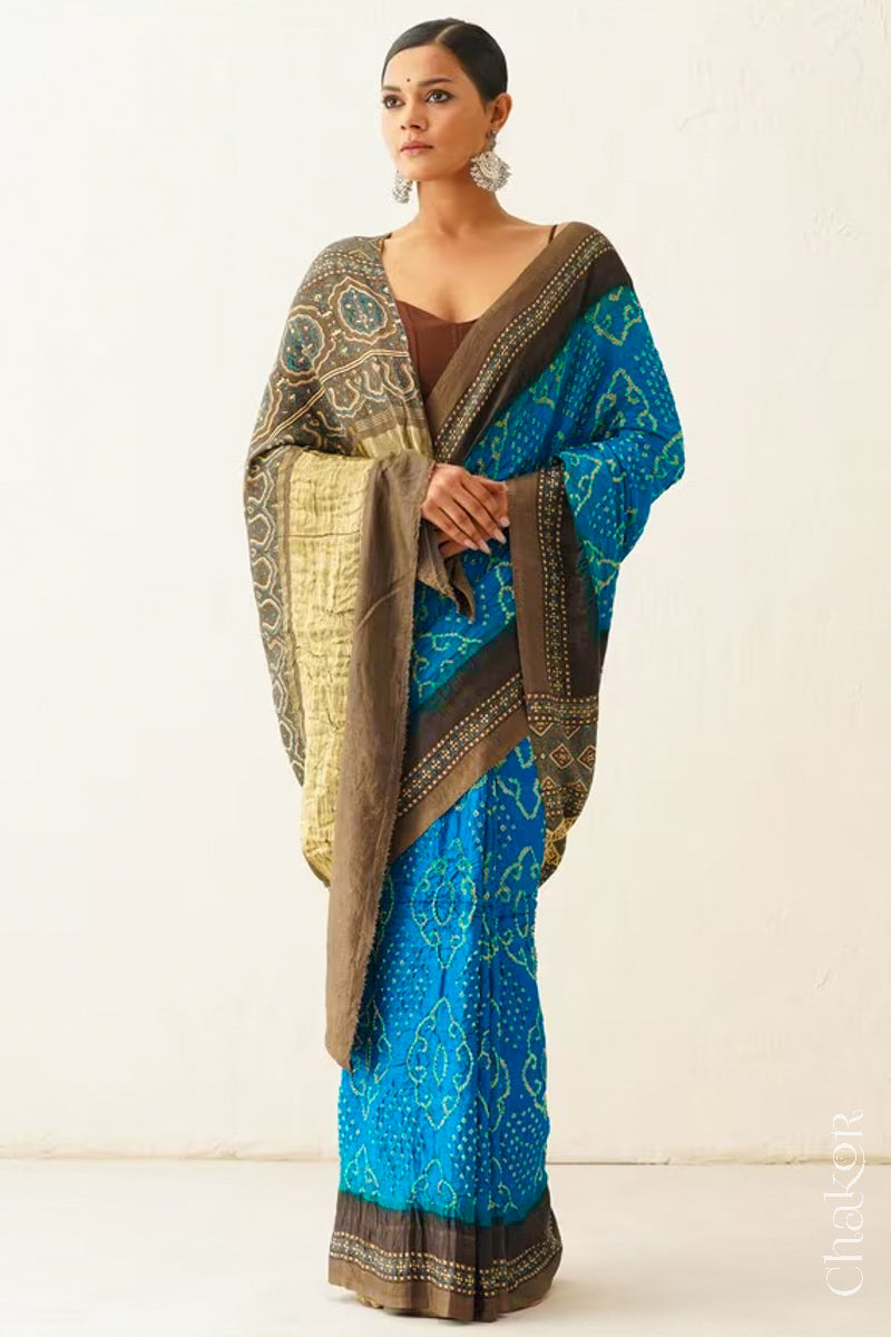 Woman wearing Peacock Blue Bandhani Saree with Brown Ajrakh printed border and pallu in pure gaji silk with traditional bandhej tie-dye, handcrafted in Kutch.