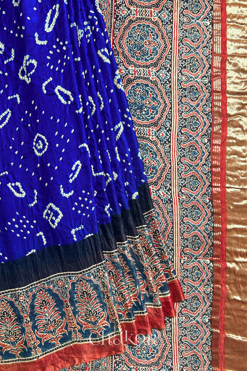 A Blue Red Bandhani Ajrakh Silk Saree with intricate bandhani motifs and a zari stripe pallu, hand block printed using natural dyes on luxurious gaji silk fabric.