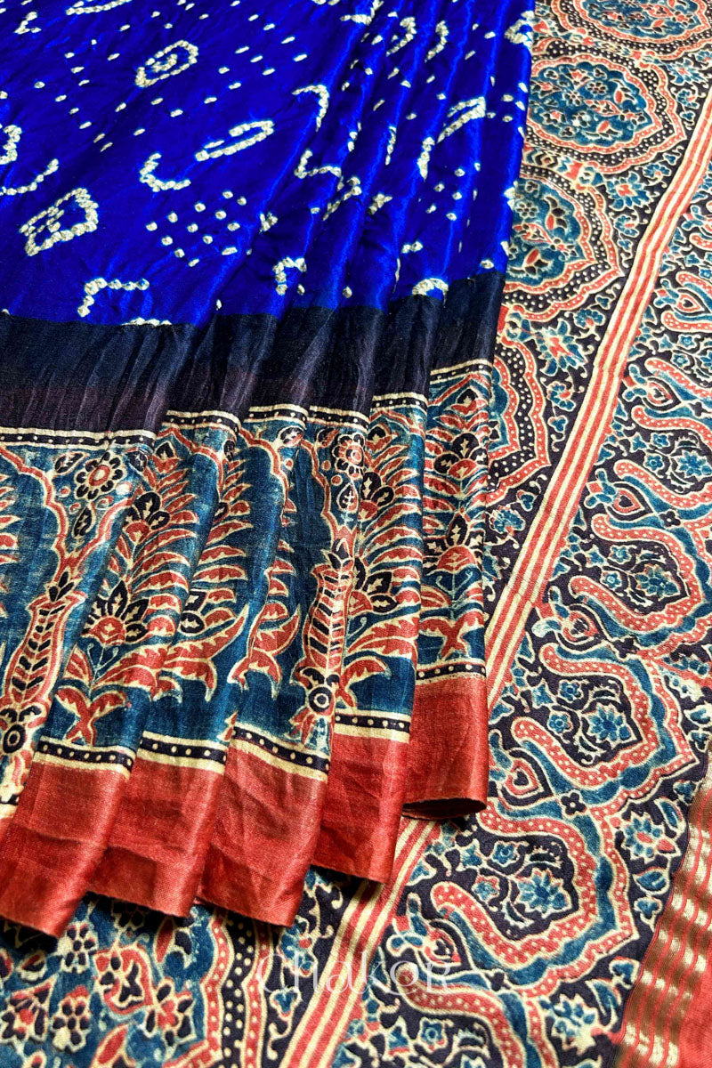 A Blue Red Bandhani Ajrakh Silk Saree with intricate bandhani motifs and a zari stripe pallu, hand block printed using natural dyes on luxurious gaji silk fabric.