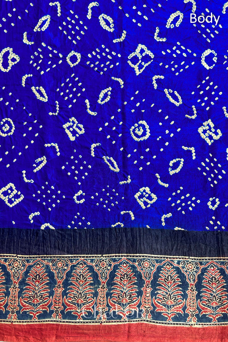 A Blue Red Bandhani Ajrakh Silk Saree with intricate bandhani motifs and a zari stripe pallu, hand block printed using natural dyes on luxurious gaji silk fabric.