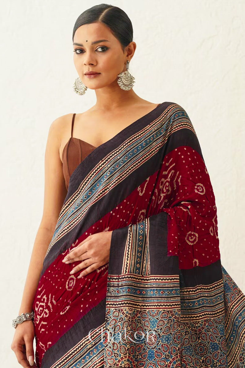 Woman wearing Maroon Bandhani Saree with Black Ajrakh printed border and pallu in pure gaji silk with traditional bandhej tie-dye, handcrafted in Kutch. 