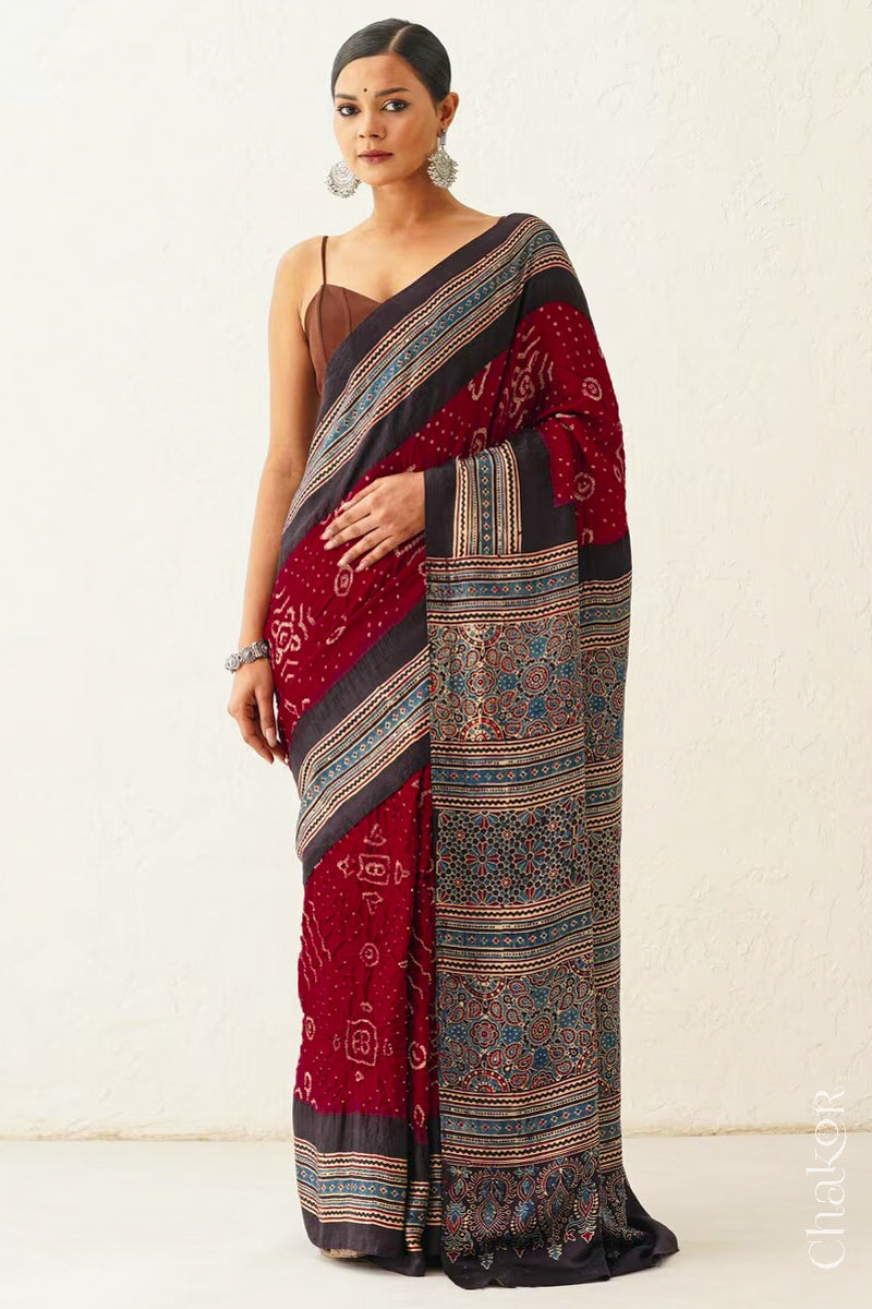 Woman wearing Maroon Bandhani Saree with Black Ajrakh printed border and pallu in pure gaji silk with traditional bandhej tie-dye, handcrafted in Kutch. 