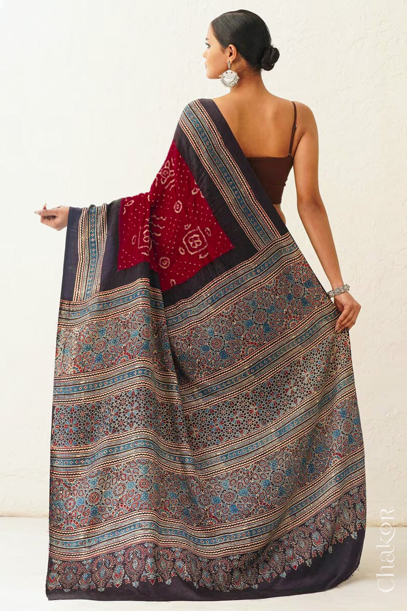 Woman wearing Maroon Bandhani Saree with Black Ajrakh printed border and pallu in pure gaji silk with traditional bandhej tie-dye, handcrafted in Kutch. 