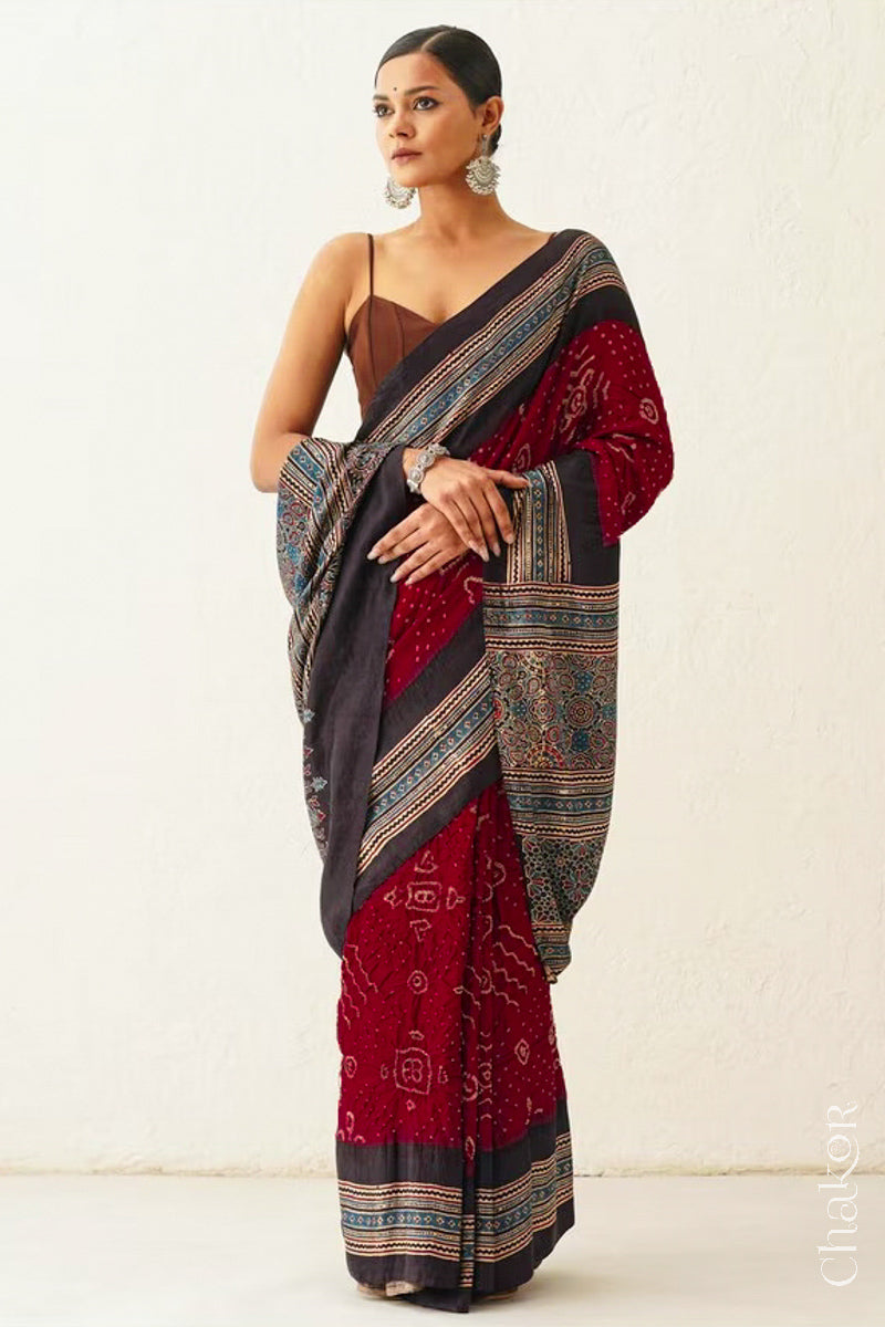 Woman wearing Maroon Bandhani Saree with Black Ajrakh printed border and pallu in pure gaji silk with traditional bandhej tie-dye, handcrafted in Kutch. 