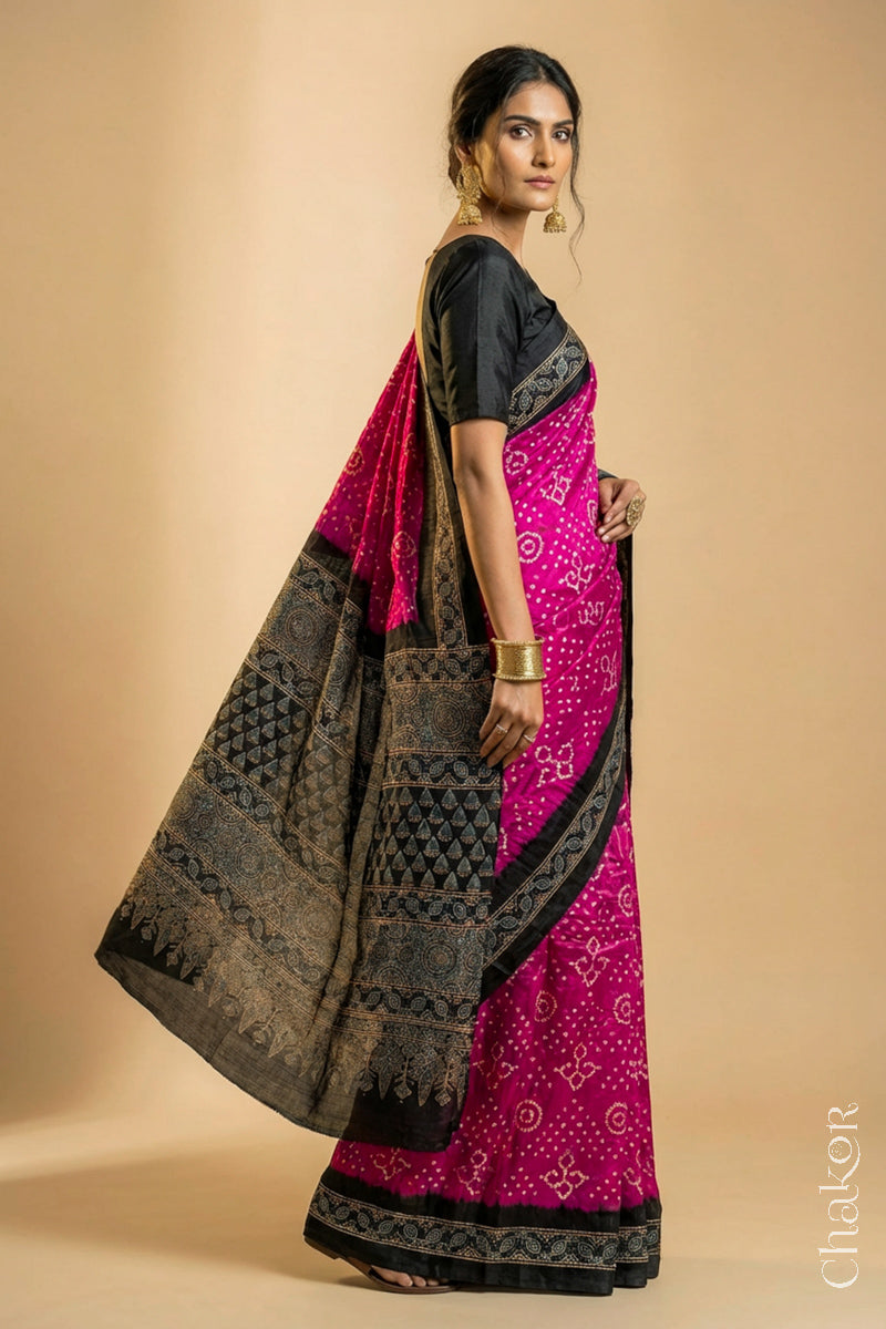 Woman wearing Pink Bandhani Saree with Black Ajrakh printed border and pallu in pure gaji silk with traditional bandhej tie-dye, handcrafted in Kutch. 