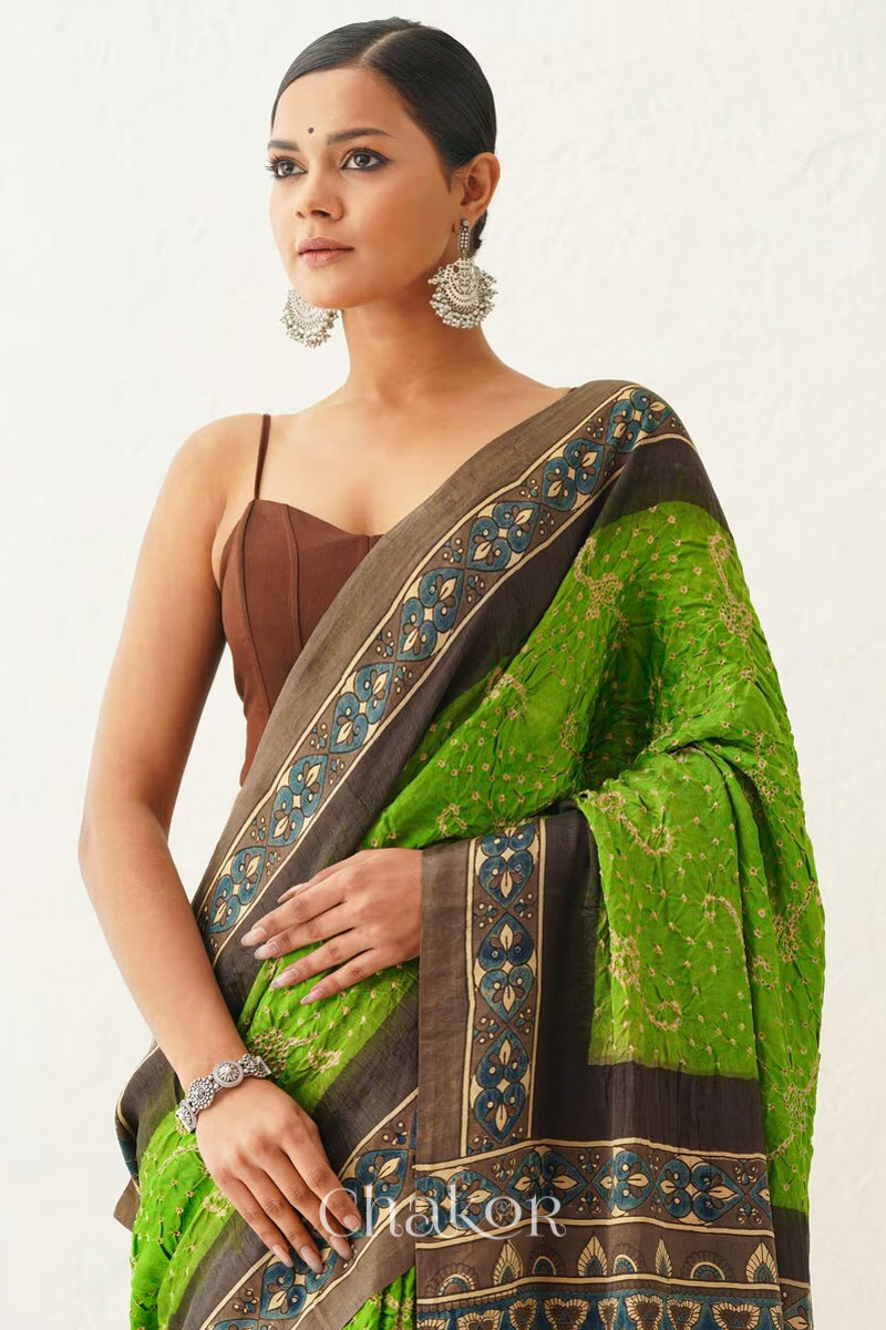 Woman wearing Parrot green Bandhani Saree with Brown Ajrakh printed border and pallu in pure gaji silk with traditional bandhej tie-dye, handcrafted in Kutch. 