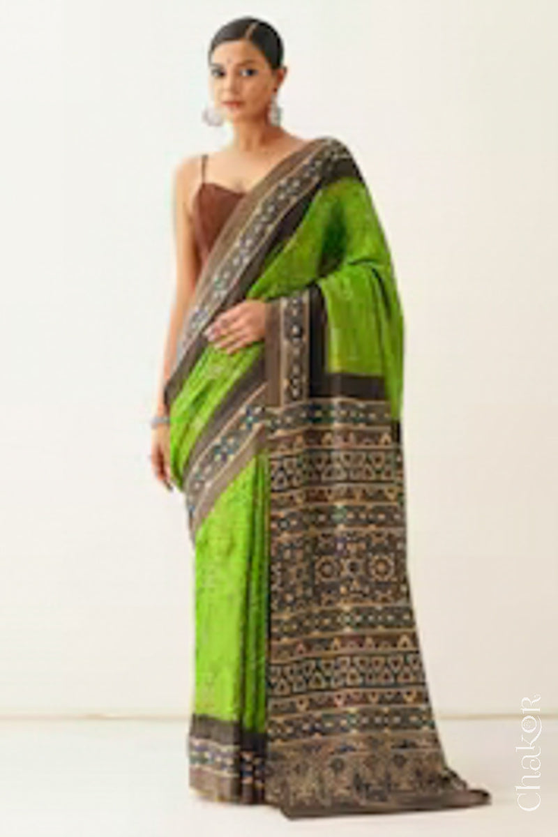 Woman wearing Parrot green Bandhani Saree with Brown Ajrakh printed border and pallu in pure gaji silk with traditional bandhej tie-dye, handcrafted in Kutch. 