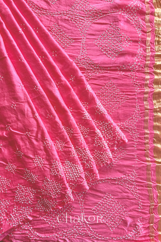 Pleats and pallu view of Handcrafted Coral Pink Bandhani Gaji Silk Saree with rai bandhej patterns and tissue pallu.