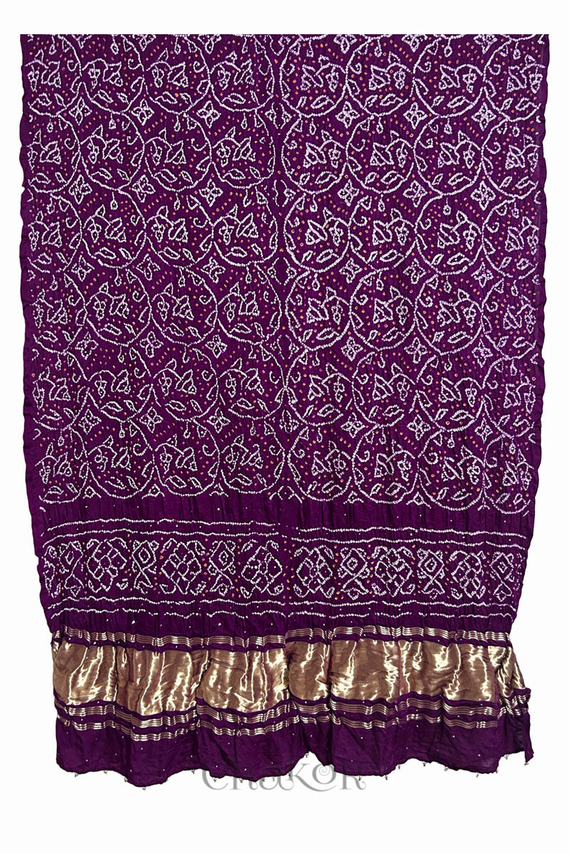 A vibrant magenta dupatta showcasing intricate rai bandhej in red & yellow with a shimmering gold band on the pallu and beads on the hem. Text reads Chakor brand watermark.
