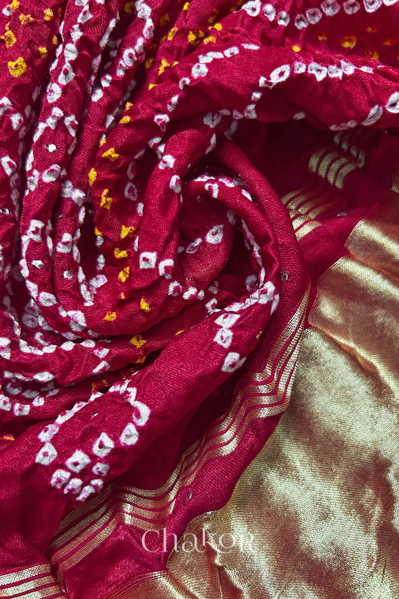 A colourful dupatta showcasing rai bandhej in red with tissue placed in swirling style. Text reads Chakor brand watermark.
