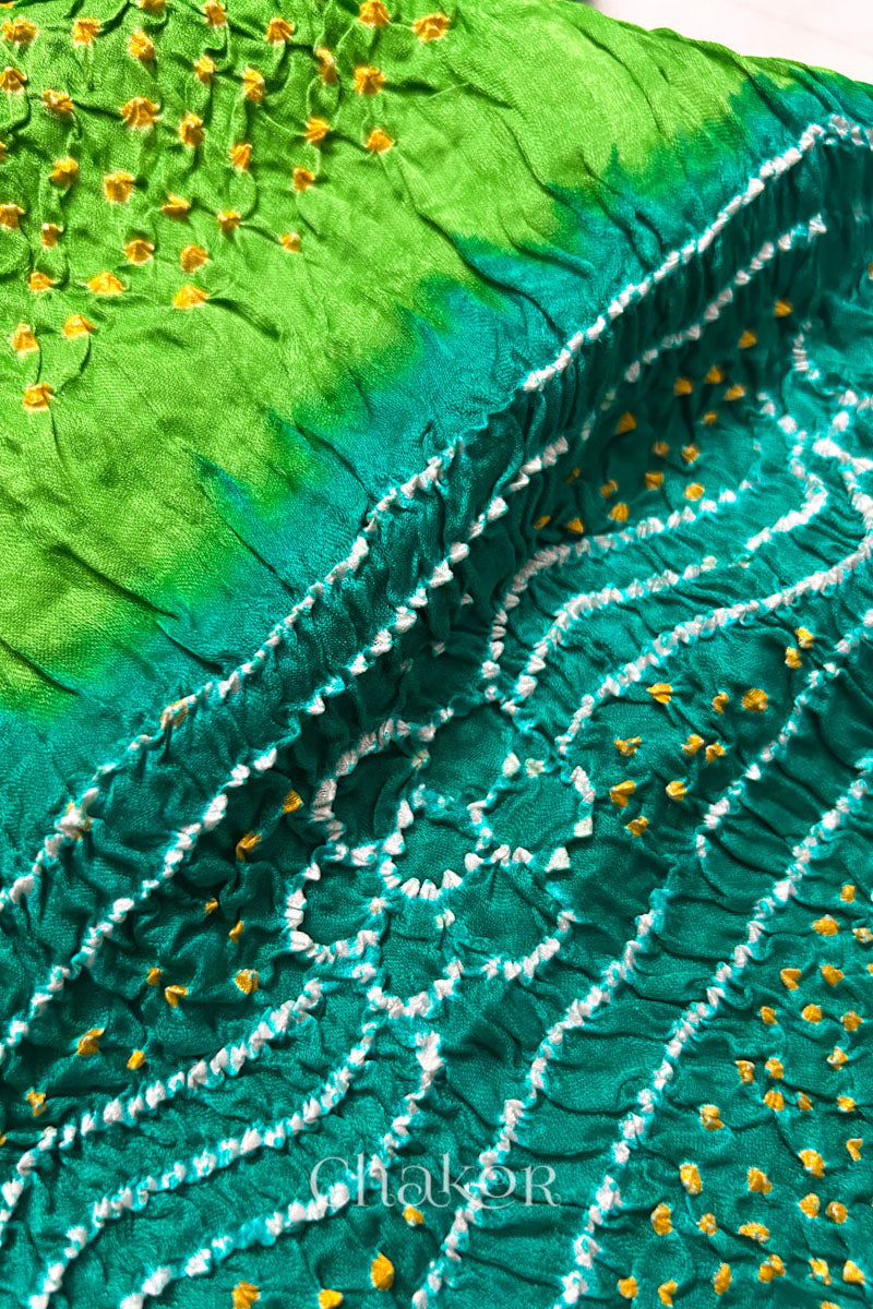 Close-up of a rai bandhej dupatta in Jade & parrot green dual colour featuring white & yellow bandhani dots.Text reads Chakor brand watermark.
