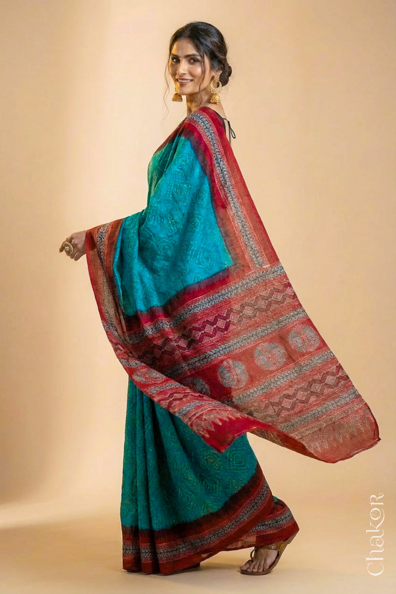Woman wearing Peacock Blue Bandhani Saree with Natural Red Ajrakh printed border and pallu in pure gaji silk with traditional bandhej tie-dye, handcrafted in Kutch. 