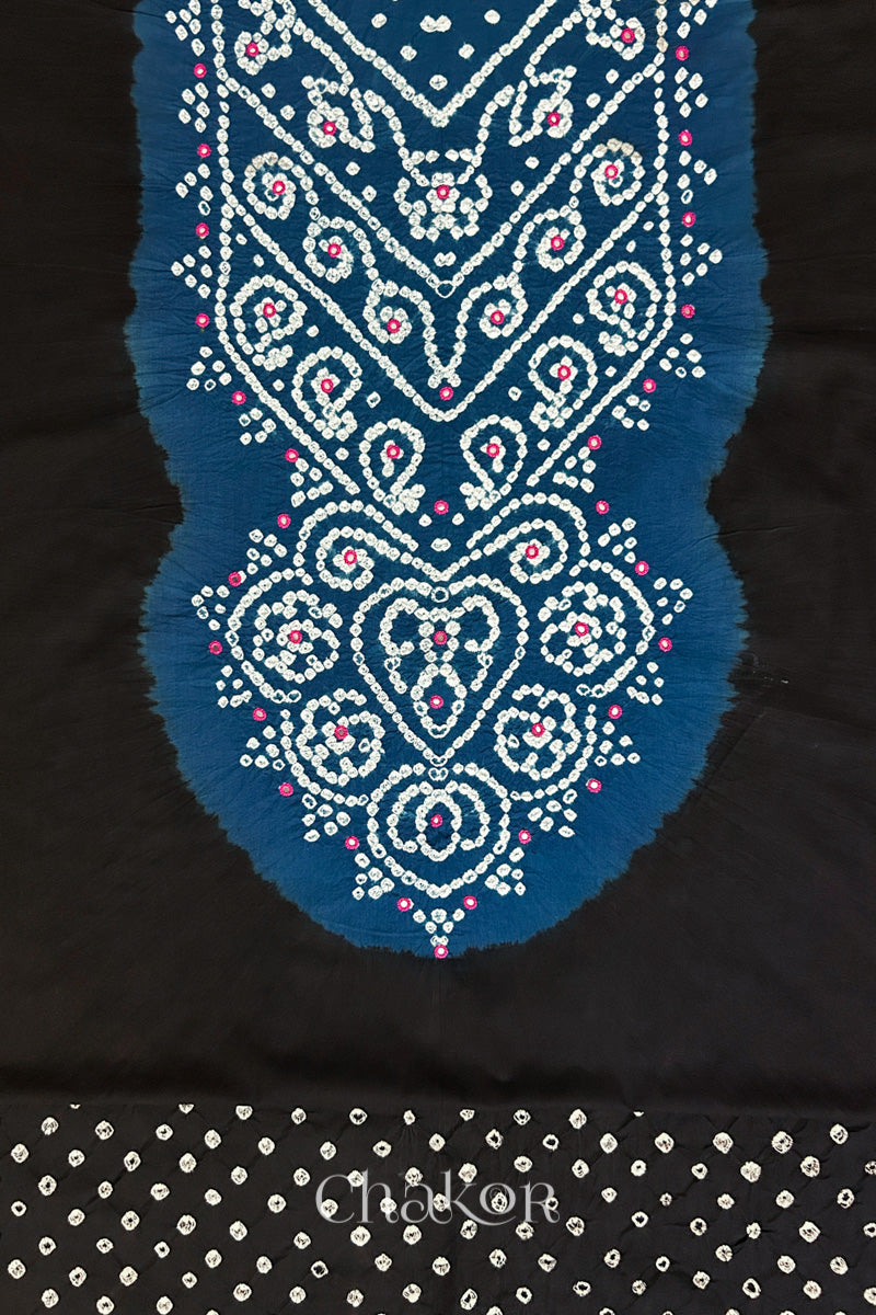 Close-up of tie dyed black kurta fabric featuring intricate bandhani and embroidered on contrasting indigo blue yoke with matching bandhani dotted bottom fabric, with Chakor brand logo.
