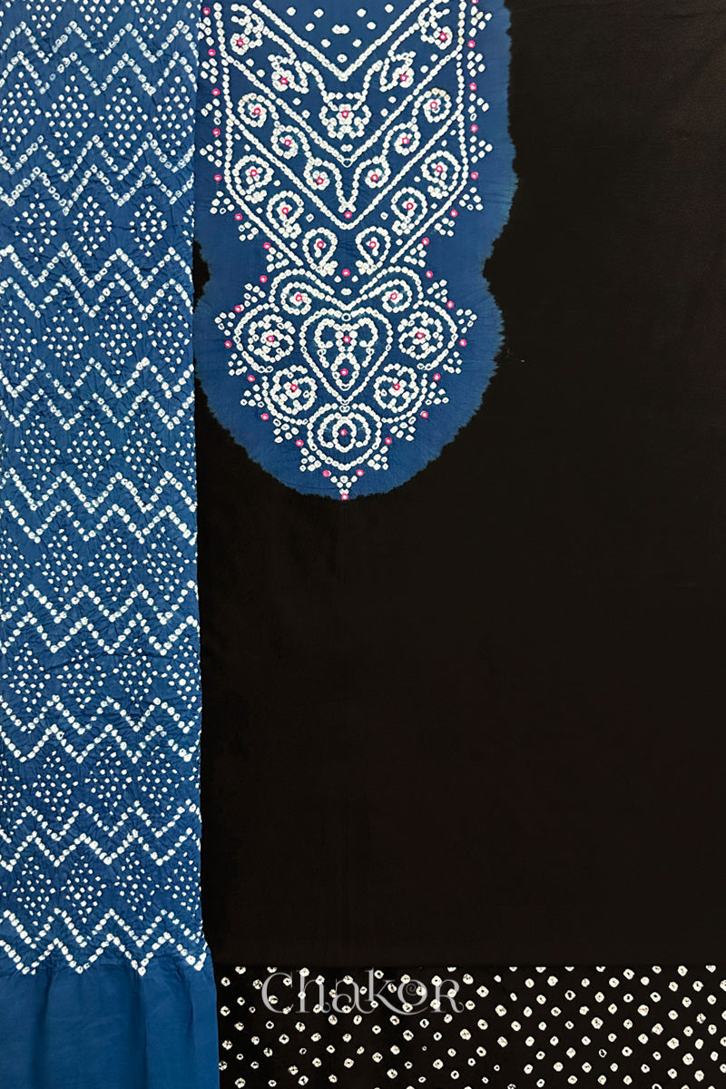 A  black kurta set fabric with intricate bandhani & mirror embroidered contrast yoke, paired with a matching bottom & contrast indigo blue odhani placed on the left side featuring a zigzag design.
