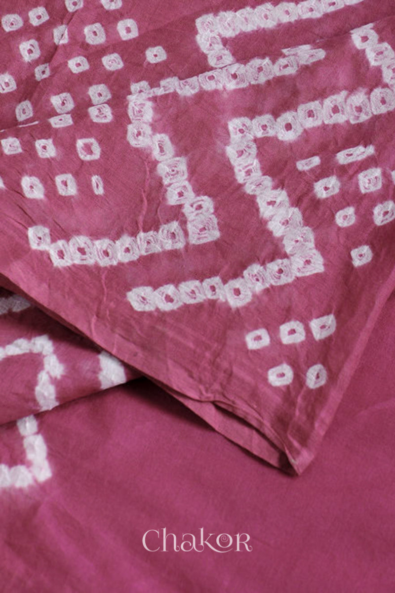 Close up plum pink cotton mul dupatta detail featuring intricate white zigzag bandhani dot patterns, showcasing traditional design.
