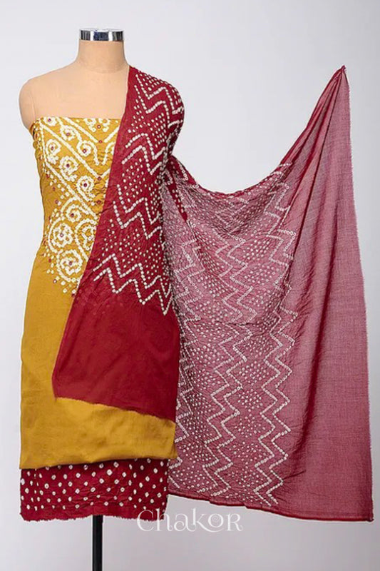A stylish kurta set fabric featuring a mustard mirror embroidered top, a bandhani red bottom, and a matching red dupatta draped elegantly. Text reads Chakor.

