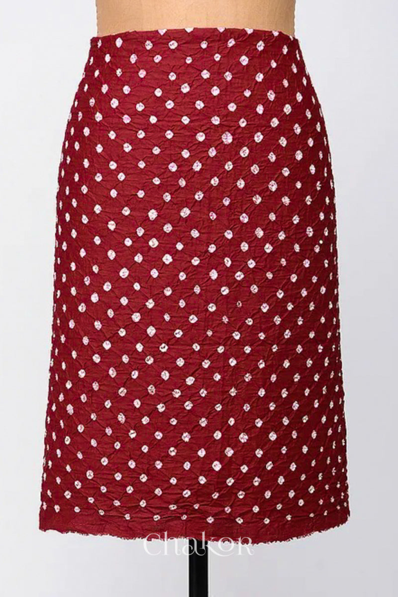 Bottom fabric in red patterned with simple bandhani tie dye dots, draped neatly on a dress form, with Chakor brand logo.
