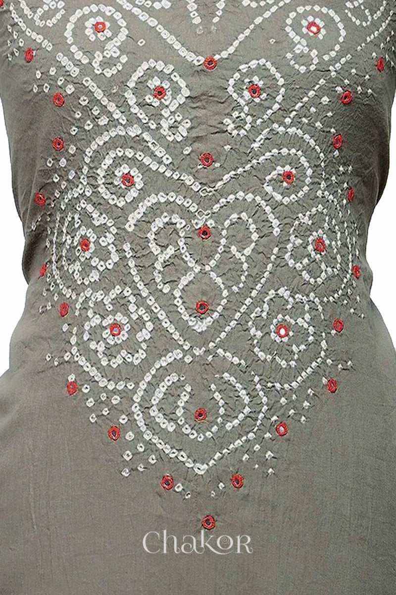 Close-up of bandhani yoke kurta fabric featuring intricate tie-dye and red embroidered patterns on an grey background, with Chakor brand logo.
