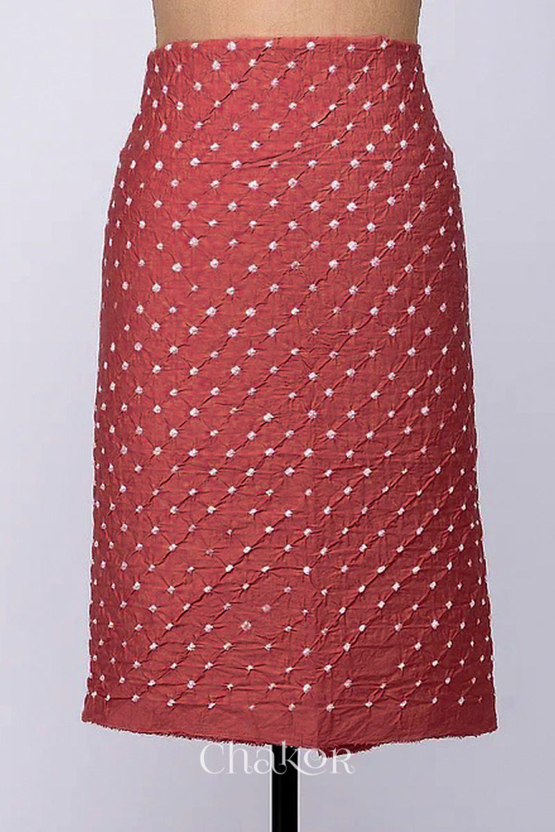 Bottom fabric in dusty red patterned with simple bandhani tie dye dots, draped neatly on a dress form, with Chakor brand logo.
