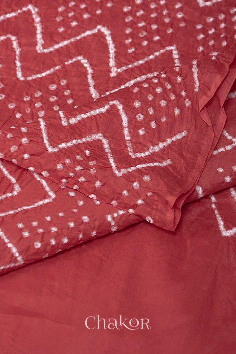 Close up dusty red cotton mul dupatta featuring intricate white zigzag bandhani dot patterns, showcasing traditional design.
