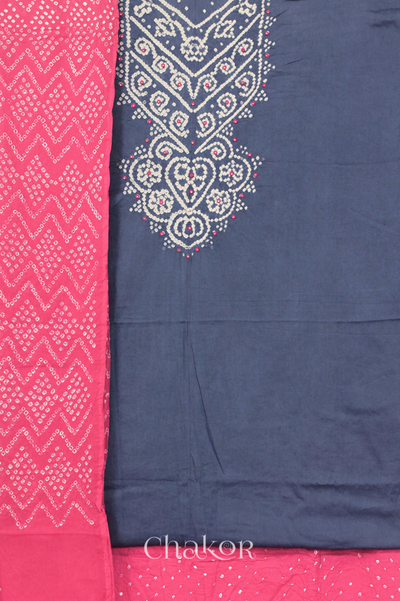 A blue grey kurta set fabric with intricate white bandhani & mirror embroidery, paired with a pink bottom & odhani featuring a zigzag design.
