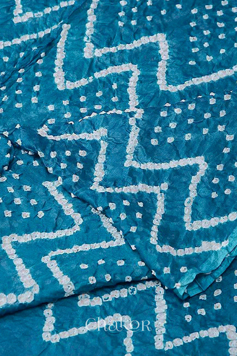 Close up of turquoise blue cotton mul dupatta featuring intricate white zigzag bandhani dot patterns, showcasing traditional design.
