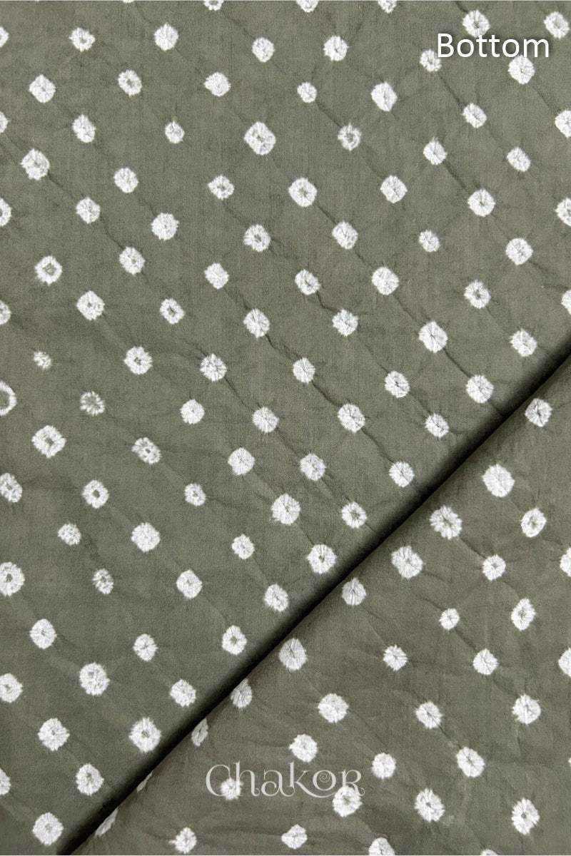Close up of Bottom fabric in grey patterned with bandhani tie dye dots, folded at the corner displaying texture and detail.