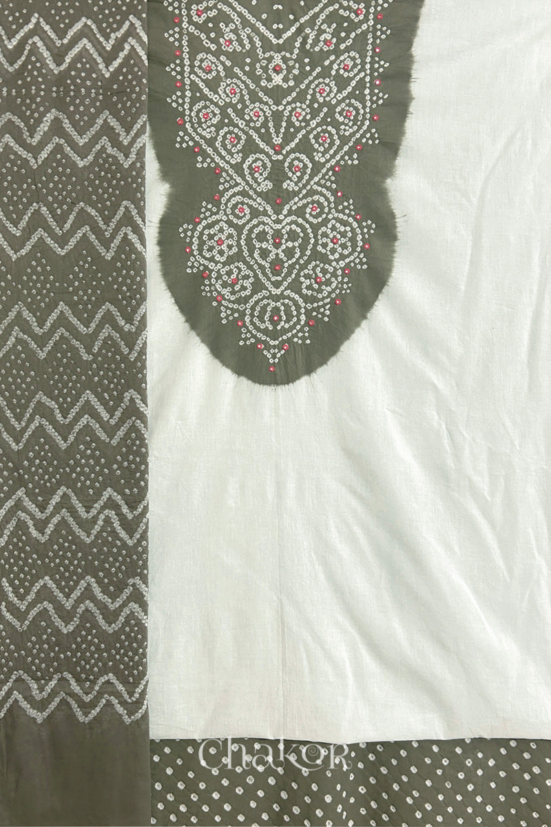 A grey- white kurta set fabric with intricate bandhani & mirror embroidery, paired with a grey bottom & odhani featuring a zigzag design.
