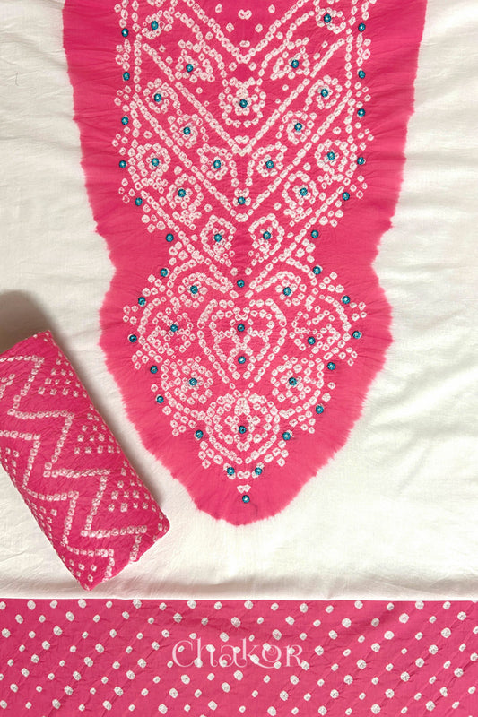 A stylish set fabric featuring a blue mirror embroidered yoke on a white kurta, bandhani pink bottom and dupatta rolled beautifully and placed on the fabric. Text reads Chakor.
