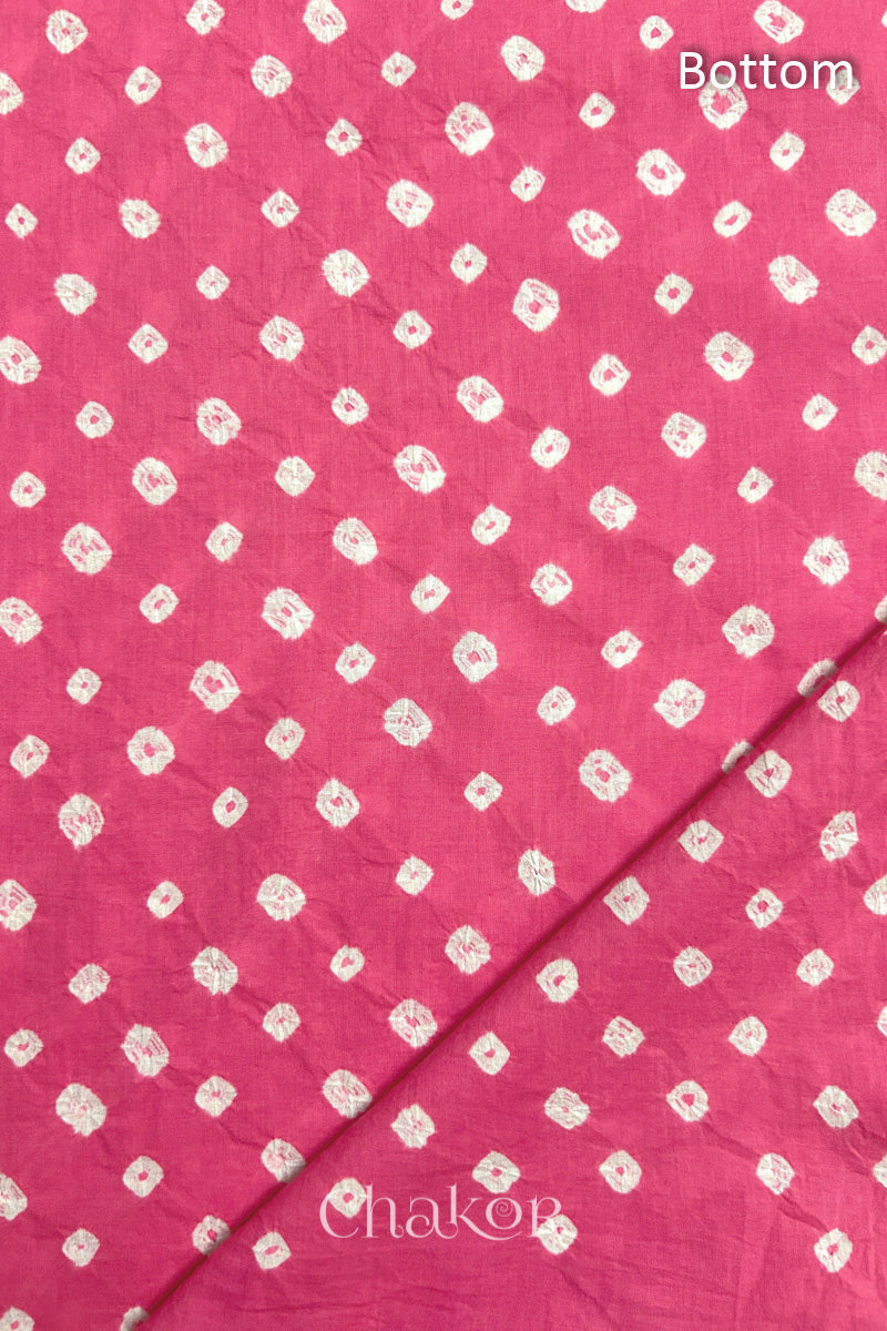 Close up of Bottom fabric in pink patterned with bandhani tie dye dots, folded at the corner displaying texture and detail.