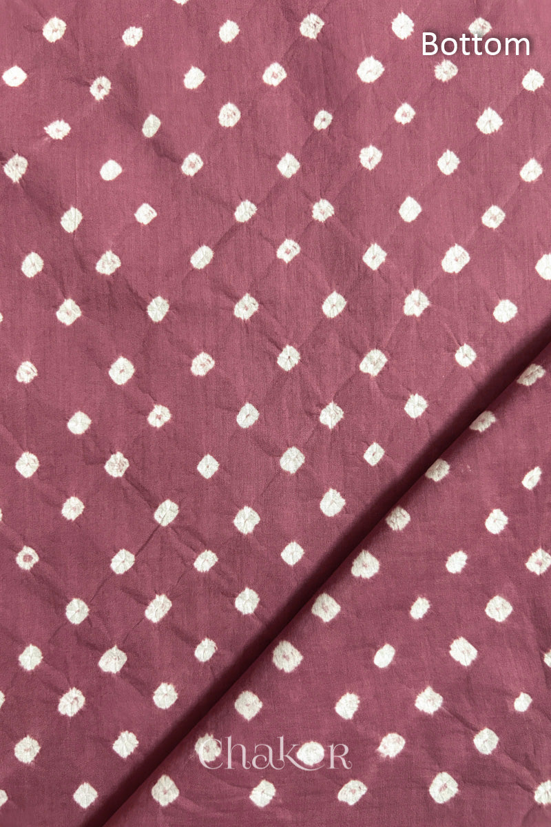 Close up of Bottom fabric in soft rose pink patterned with bandhani tie dye dots, folded at the corner displaying texture and detail.