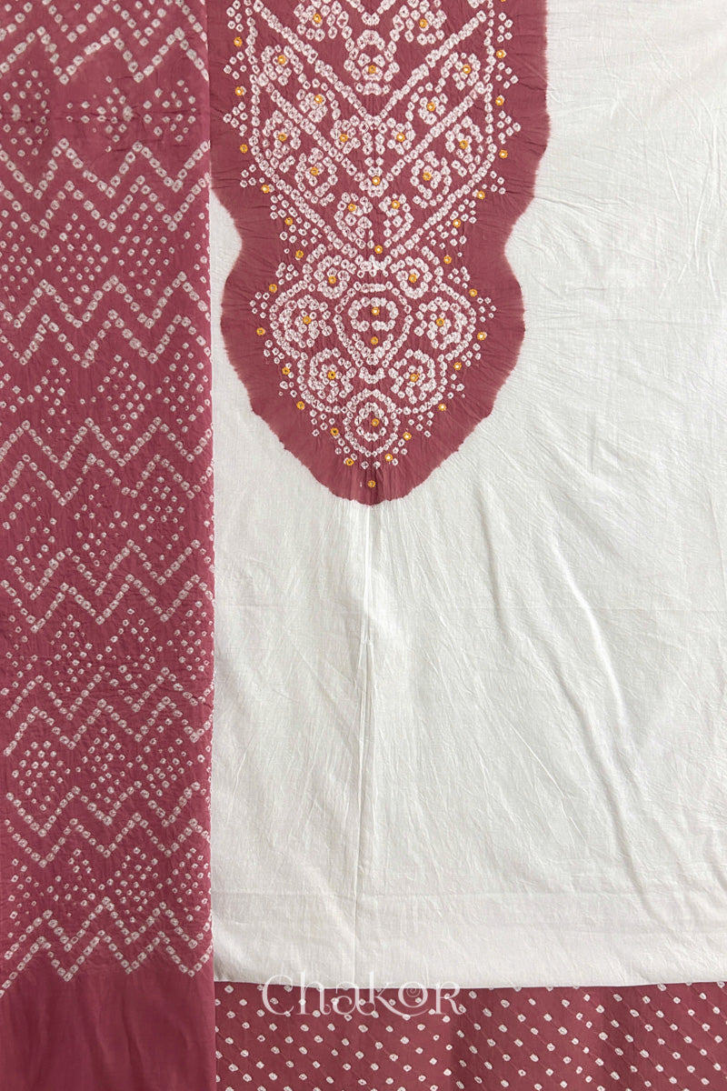 A soft rose pink- white kurta set fabric with intricate bandhani & mirror embroidery, paired with a soft rose pink bottom & odhani featuring a zigzag design.