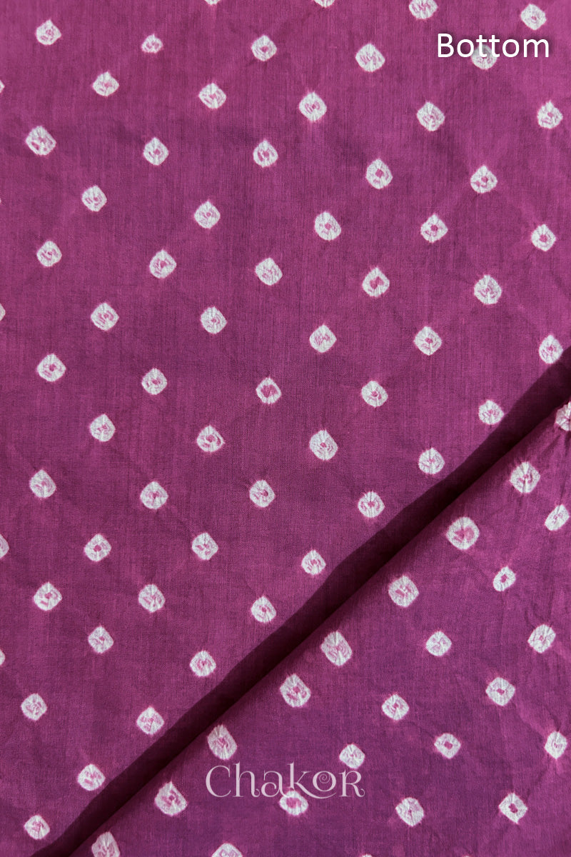 Close up of Bottom fabric in deep violet patterned with bandhani tie dye dots, folded at the corner displaying texture and detail.