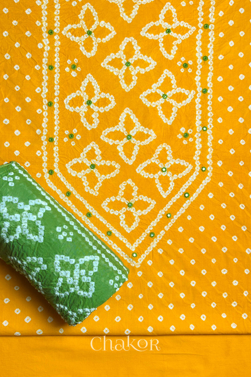 Front yoke detail of Yellow Bandhani cotton kurta fabric with hand embroidery and mirror work and Green dupatta rolled up.
