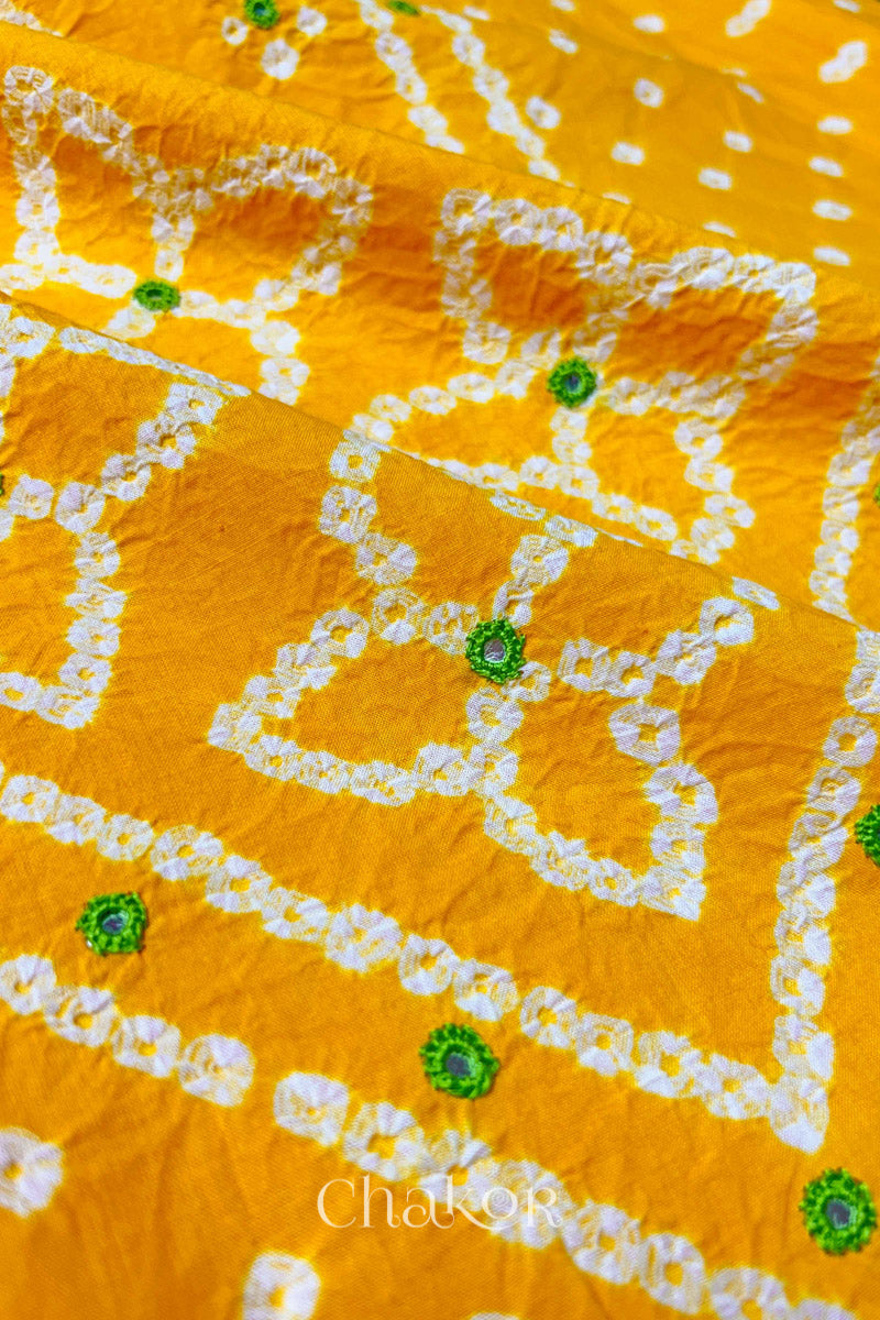 Hand tied Bandhani floral motif with colourful mirror embroidery on Yellow cotton fabric.

