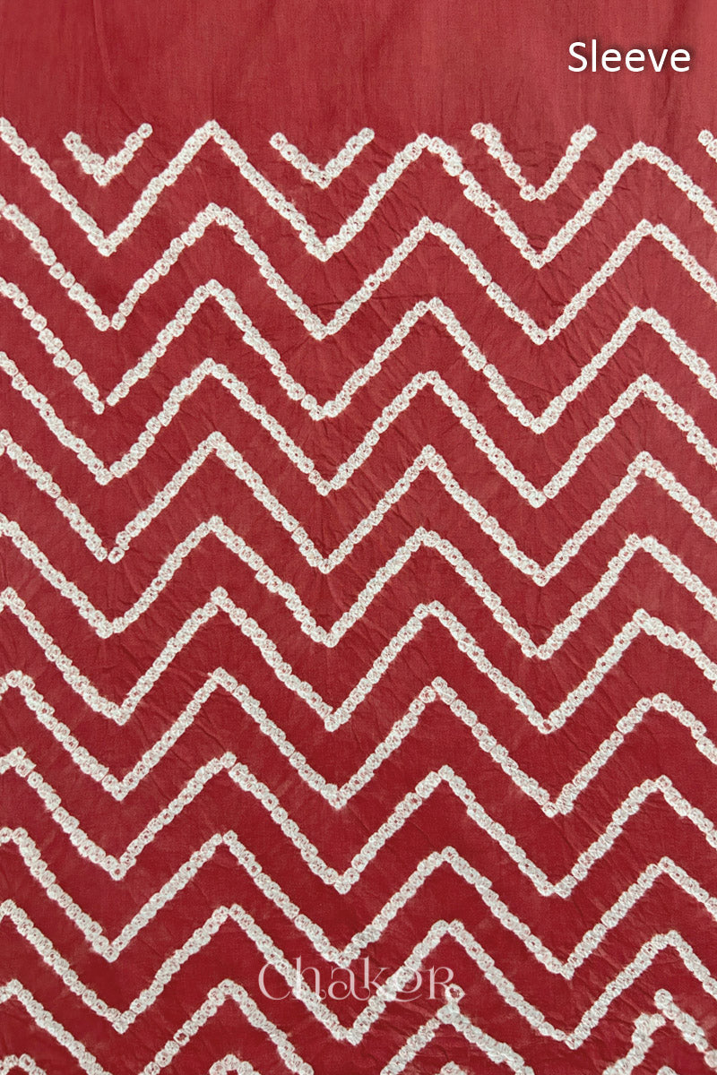 Close-up of  brick red bandhani fabric featuring chevron tie-dye design, with Chakor brand logo. Text reads sleeve details.