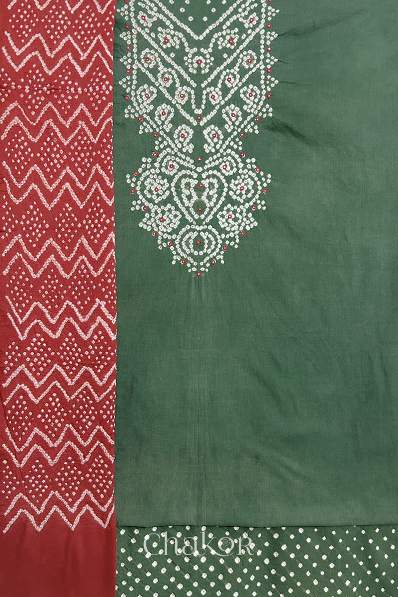 A  moss green kurta set fabric with intricate bandhani & mirror embroidered yoke, paired with a matching bottom & brick red odhani placed on the left side featuring a zigzag design.
