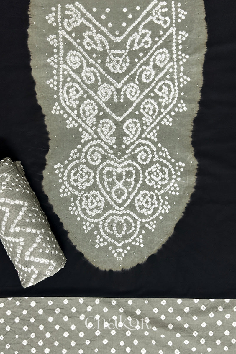 A classic black set fabric featuring sparkly mukaish embroidered contrast cement grey yoke & bottom and dupatta rolled beautifully and placed on the fabric. Text reads Chakor.
