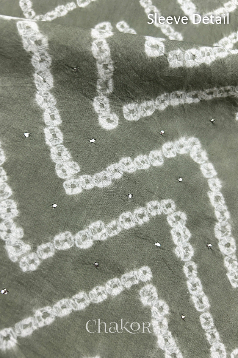 Close-up of  black bandhani fabric featuring chevron tie-dye design, showcasing sparkly mukaish embroidery with Chakor brand watermark. Text reads sleeve details.
