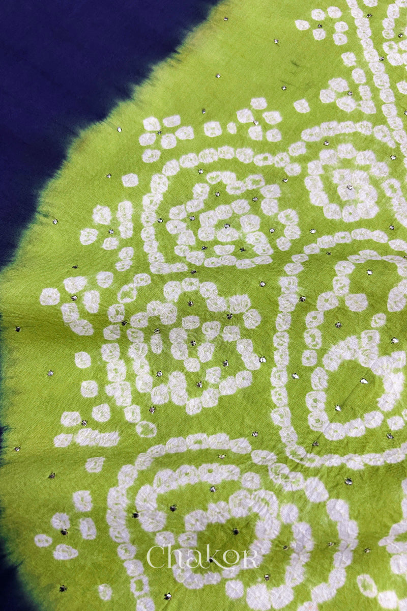 Close-up of navy fabric adorned with intricate traditional bandhani patterns and sparkly mukaish embroidery on lime green yoke, showcasing beautiful craftsmanship.

