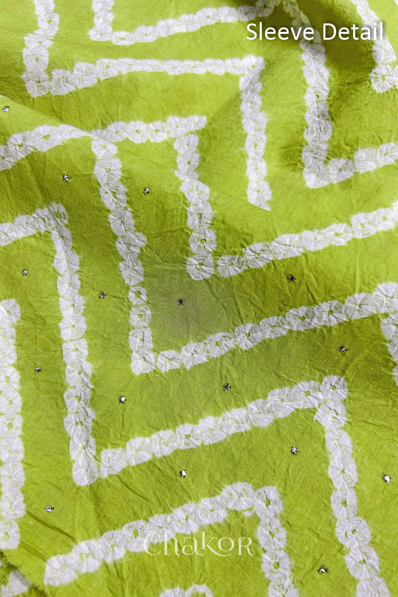 Close-up of lime green bandhani fabric featuring chevron tie-dye design, showcasing sparkly mukaish embroidery with Chakor brand watermark. Text reads sleeve details.
