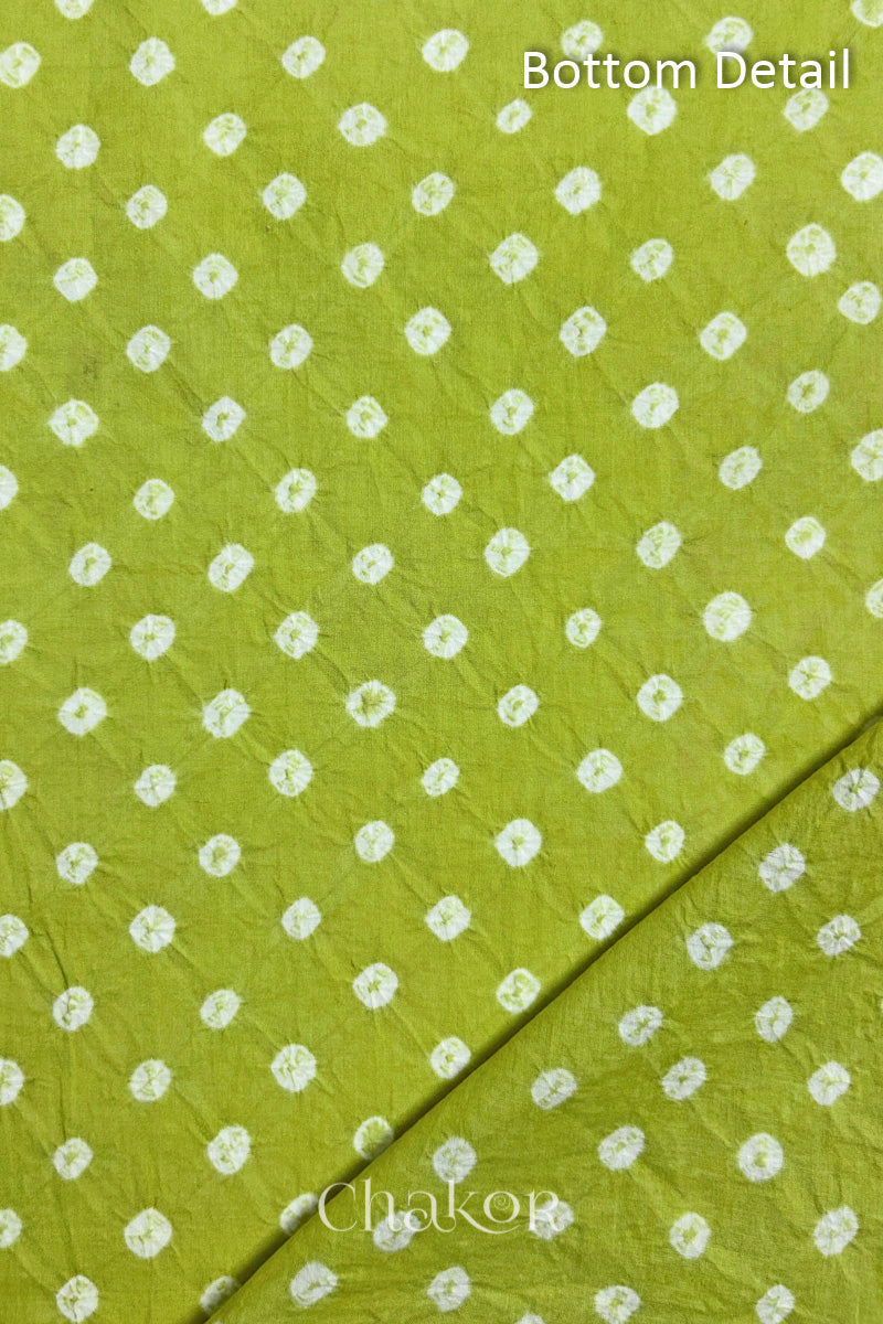 Close up of bottom fabric in lime green patterned with bandhani tie dye dots, folded at the corner displaying texture and detail. Text reads bottom.
