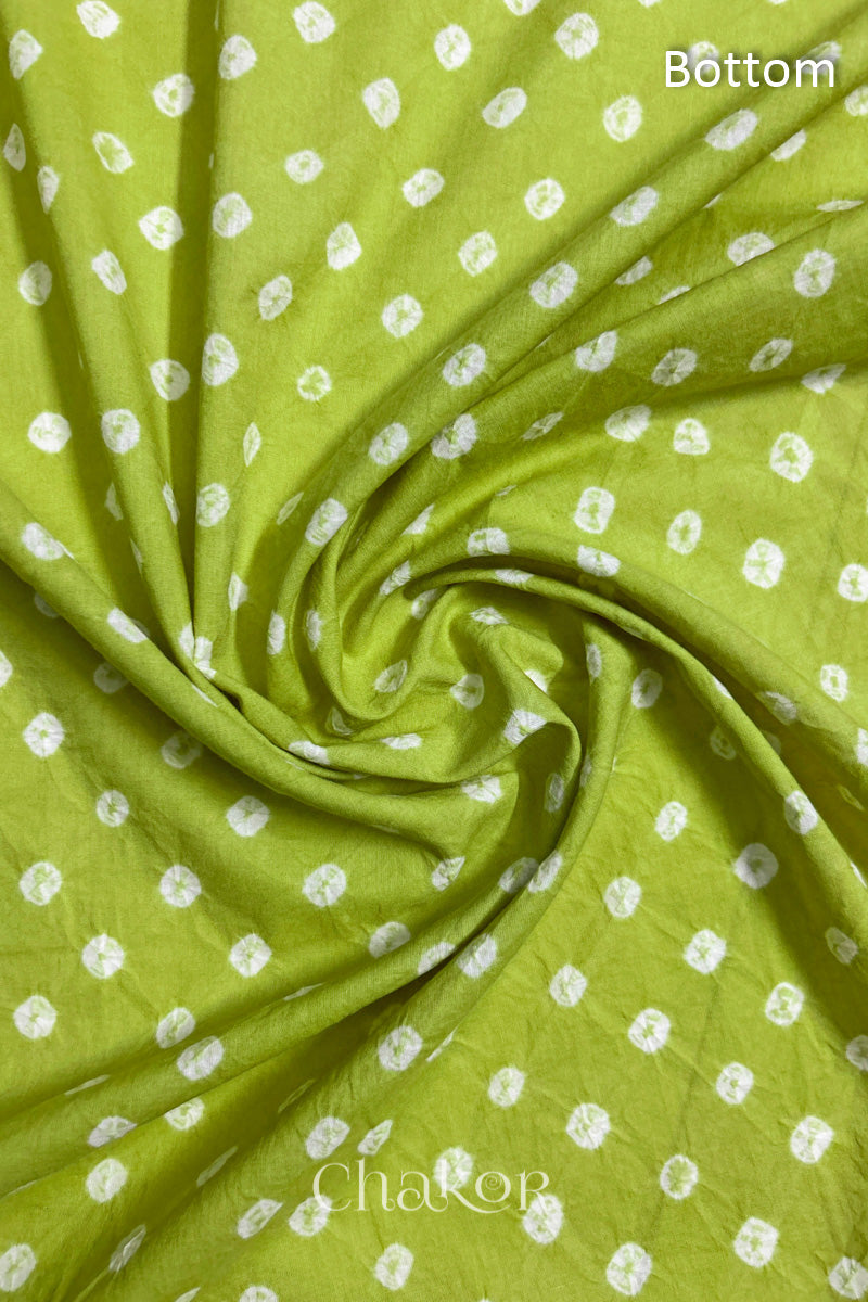 Close-up of lime green fabric featuring bandhani pattern of white dots, arranged in a swirly style showcasing the textile's texture and design details.Text reads bottom details.
