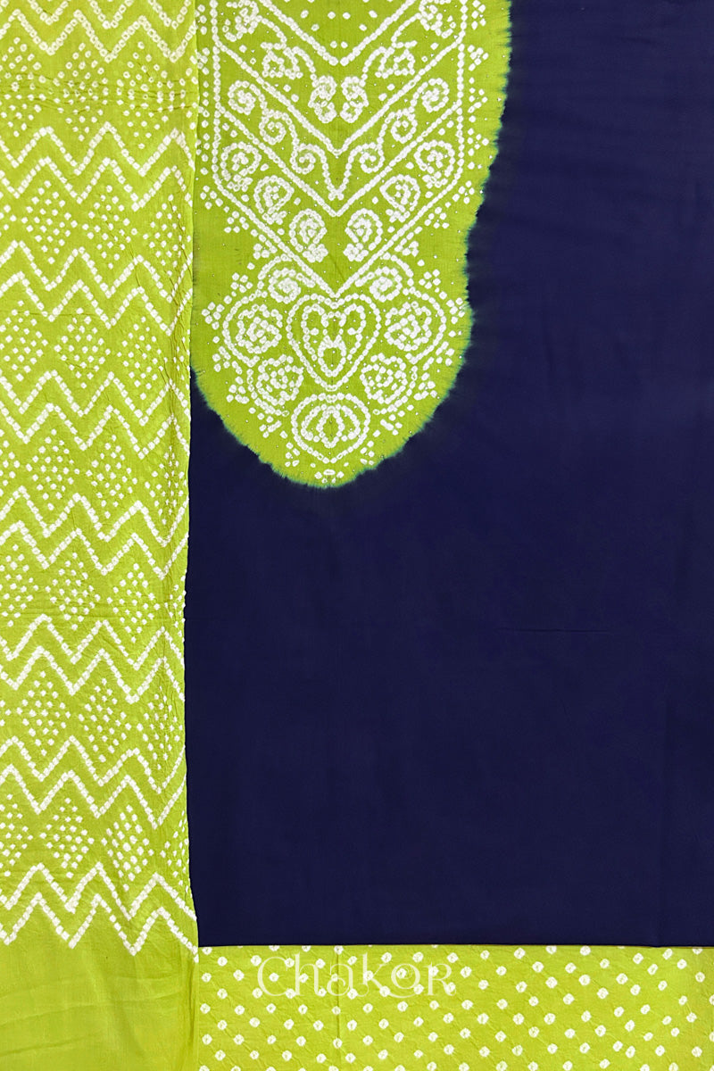 A navy kurta set fabric with intricate bandhani & lime green yoke with sparkly mukaish embroidery, paired with a bottom & odhani placed on the left side featuring a zigzag design.

