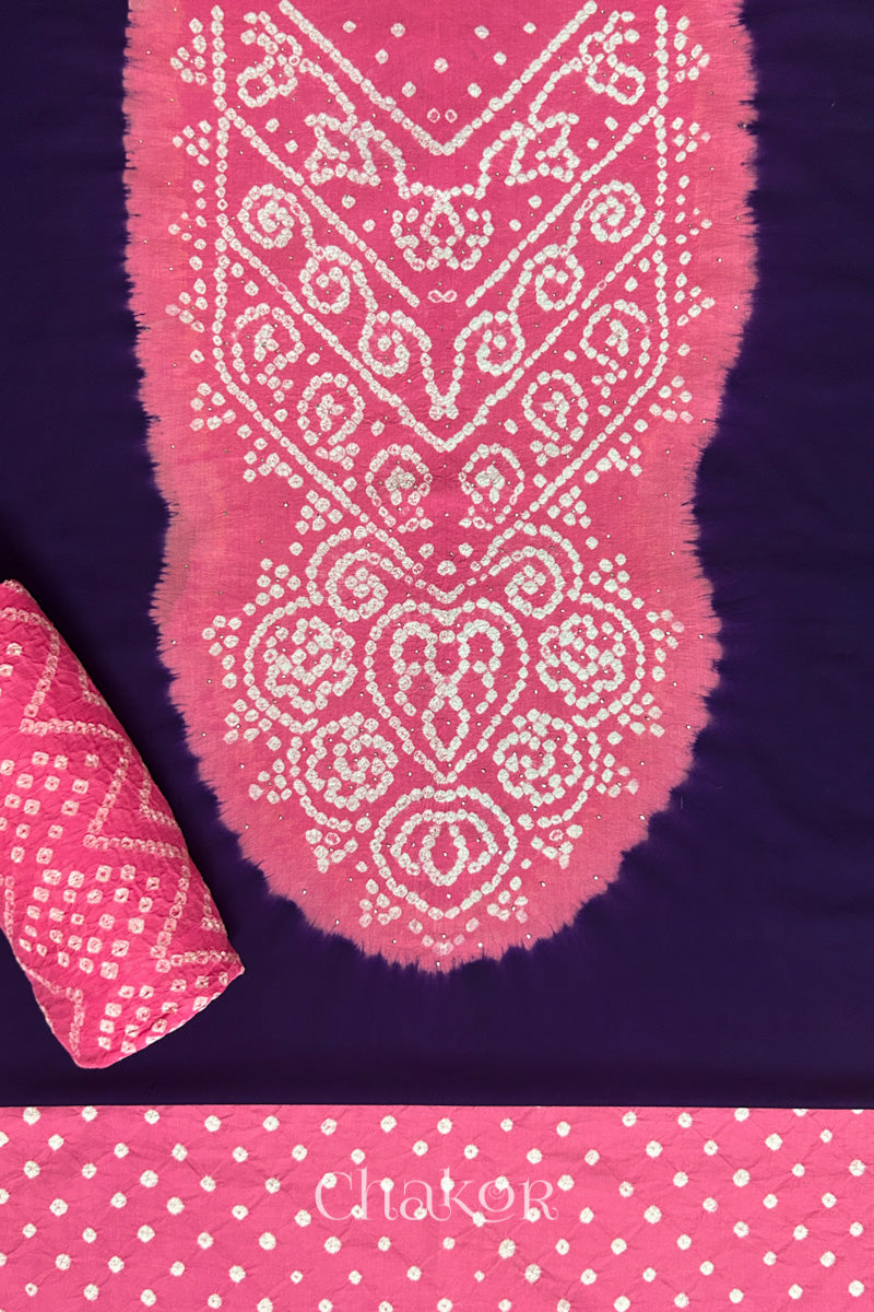 A classic dark purple set fabric featuring sparkly mukaish embroidered contrast pink yoke & bottom and dupatta rolled beautifully and placed on the fabric. Text reads Chakor.
