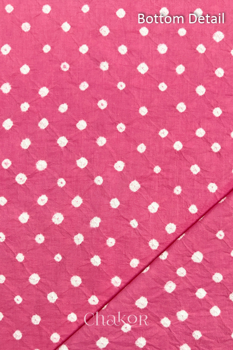 Close up of bottom fabric in pink patterned with bandhani tie dye dots, folded at the corner displaying texture and detail. Text reads bottom.
