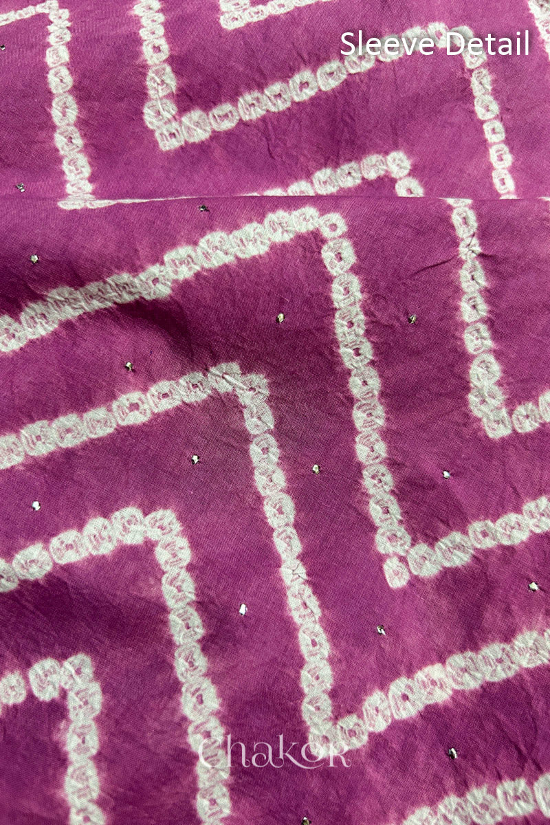Close-up of violet puprle bandhani fabric featuring chevron tie-dye design, showcasing sparkly mukaish embroidery with Chakor brand watermark. Text reads sleeve details.
