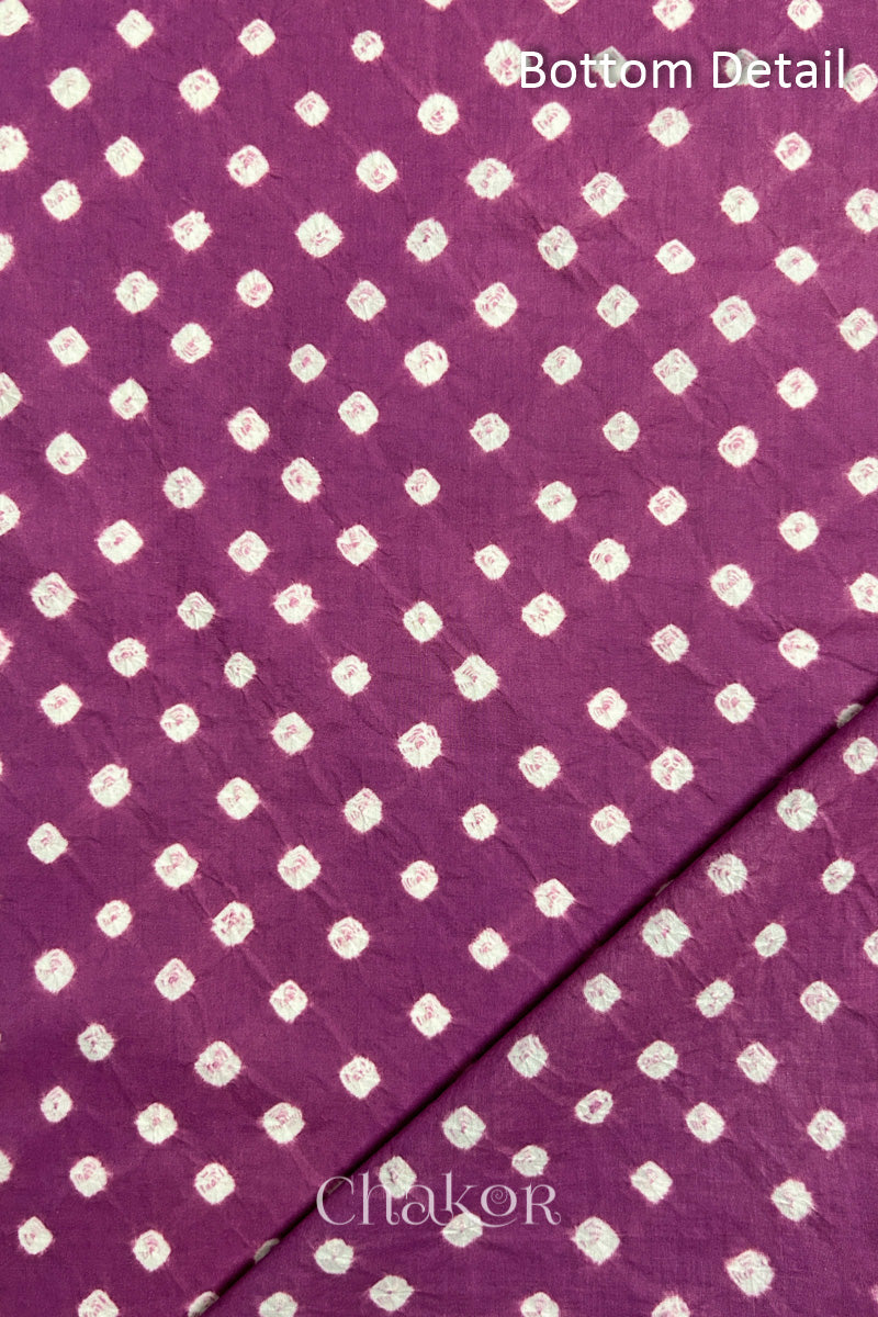 Close up of bottom fabric in violet puprle patterned with bandhani tie dye dots, folded at the corner displaying texture and detail. Text reads bottom.
